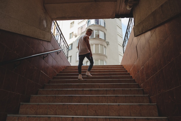 Kletternde Treppe des jungen Mannes in der Fußgängeruntergrundbahn