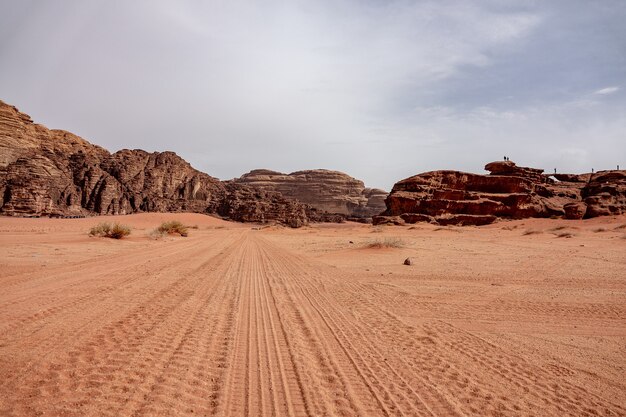 Klippen und Höhlen auf einer Wüste voller trockenem Gras unter einem bewölkten Himmel während des Tages