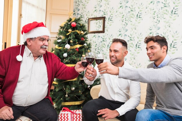 Klirrende Gläser der Leute nähern sich Weihnachtsbaum