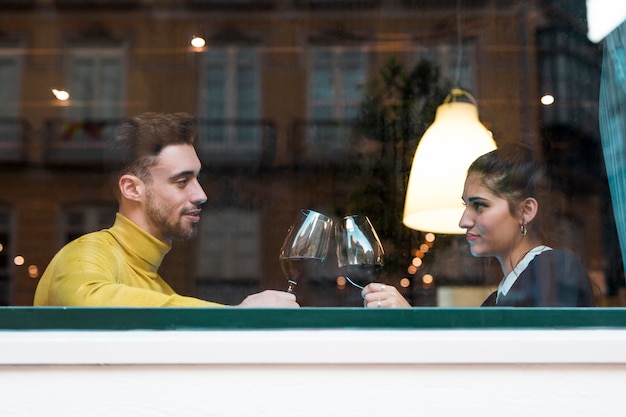 Klopfengläser des jungen Mannes und der Frau Weins im Restaurant