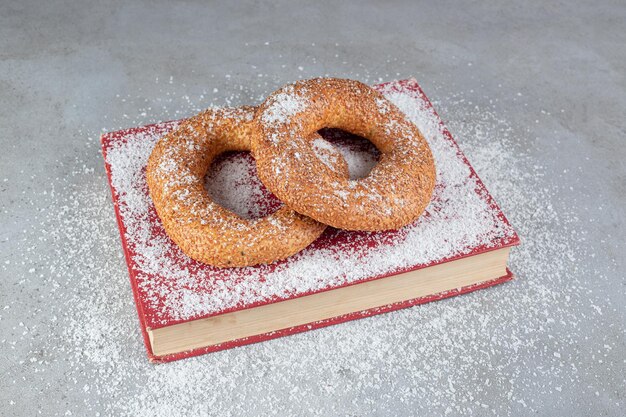 Knackige Bagels mit Sesamüberzug auf einem Tablett mit Kokosnusspulver auf Marmoroberflächeq