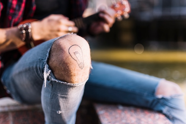 Knie des jungen, der die ukulele spielt