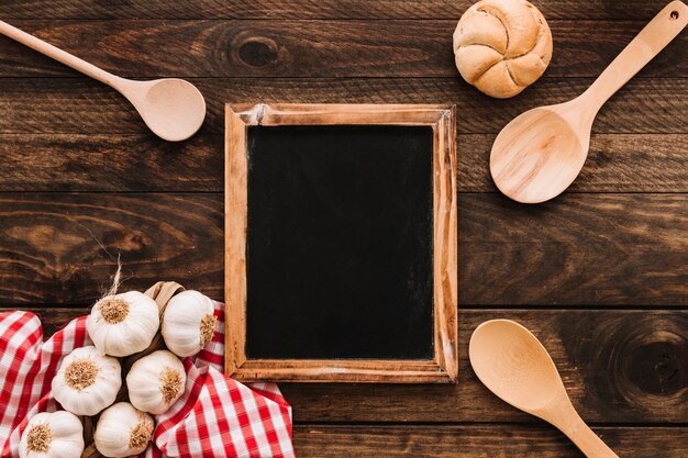 Knoblauch und Brötchen nahe Löffeln und Tafel