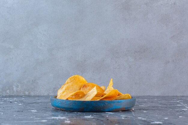 Knusprig-würzige Kartoffelchips in Holzplatte, auf der Marmoroberfläche