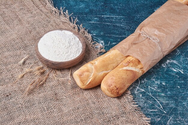 Knusprige Baguettes auf blauem Tisch in Papierverpackung.