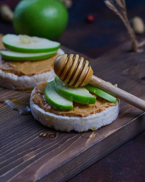 Knuspriges natürliches Erdnussbuttersandwich mit Reiskuchenbrot und grünen Apfelscheiben und Honig.