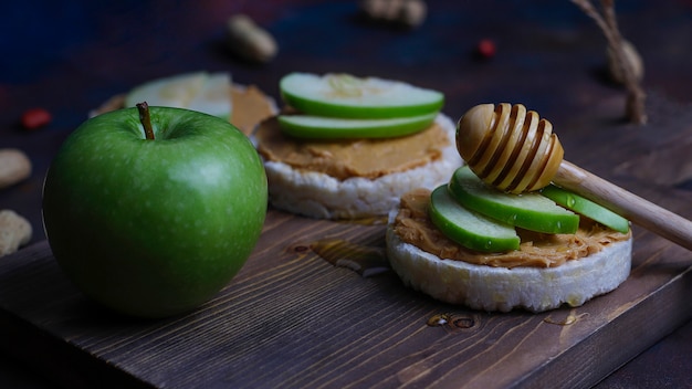 Knuspriges natürliches Erdnussbuttersandwich mit Reiskuchenbrot und grünen Apfelscheiben und Honig.