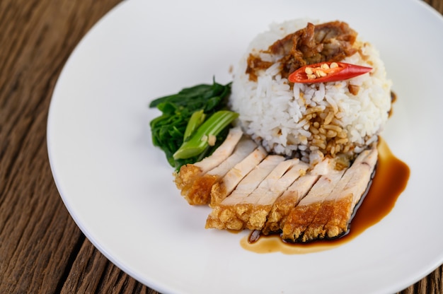 Knuspriges Schweinefleisch auf einem weißen Teller mit Sauce und Chili in zwei Hälften geteilt.