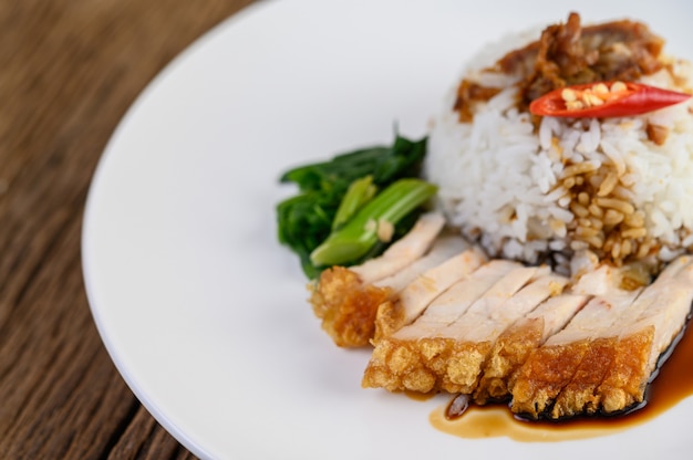 Knuspriges Schweinefleisch auf einem weißen Teller mit Sauce und Chili in zwei Hälften geteilt.