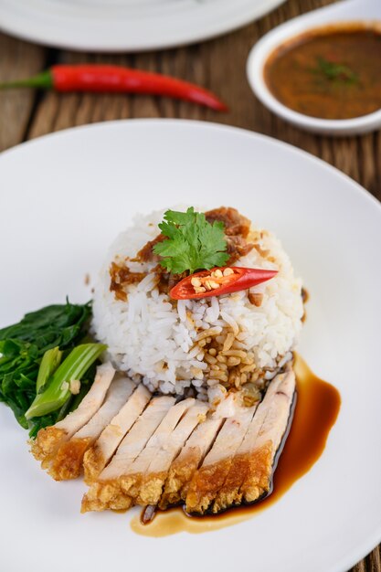 Knuspriges Schweinefleisch auf einem weißen Teller mit Sauce und Chili in zwei Hälften geteilt.