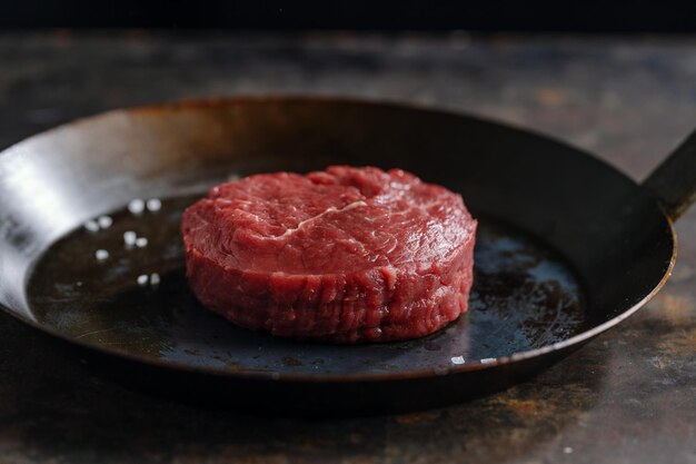 Koch, der frisches Fleisch an Bord kocht Dunkler Hintergrund Kochkonzept