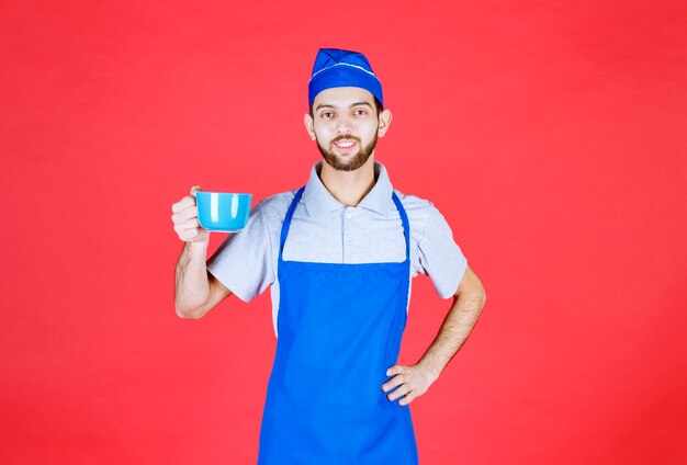 Koch in blauer Schürze mit einer blauen Keramikschale.
