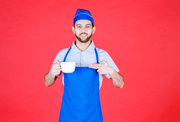 Koch in blauer Schürze mit einer weißen Keramikschale.