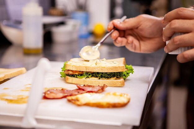 Koch macht Sandwich mit frischen Zutaten. Leckere Ernährung