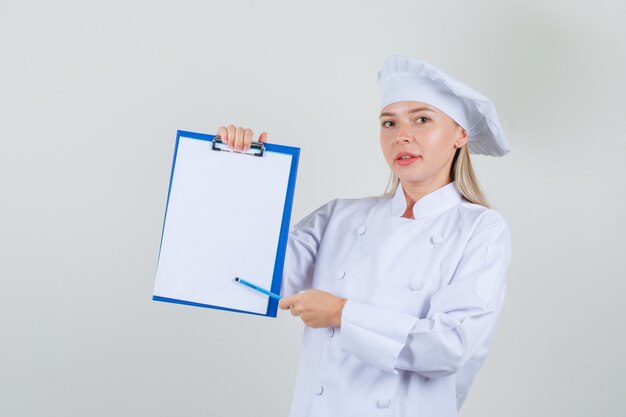 Köchin, die Bleistift auf Zwischenablage in weißer Uniform zeigt