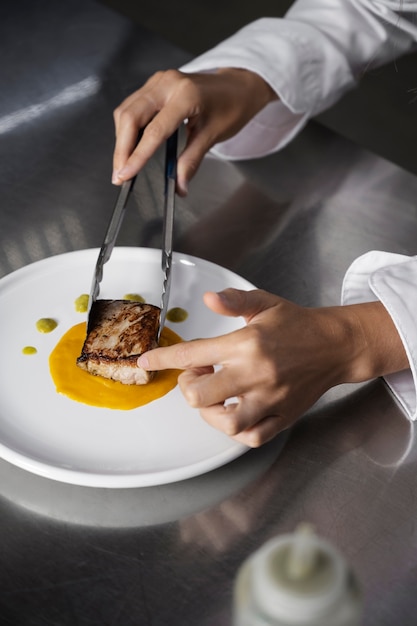 Kostenloses Foto köchin in der küche, die teller mit steak zubereitet