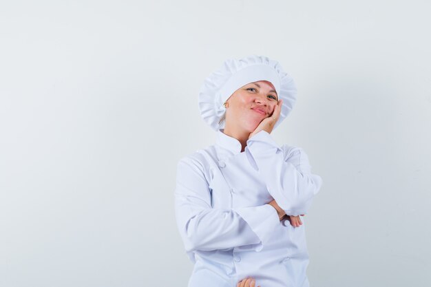 Köchin in weißer Uniform, die Hand auf Wange hält und optimistisch schaut