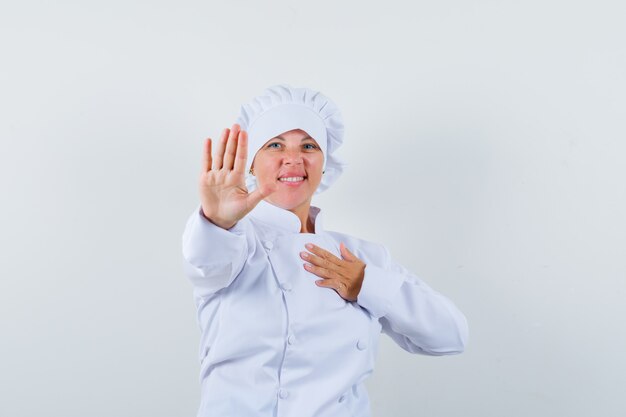 Köchin in weißer Uniform, die Stoppgeste zeigt und selbstbewusst aussieht