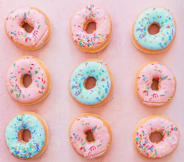 Köstliche Donuts mit Streuseln auf rosa Hintergrund