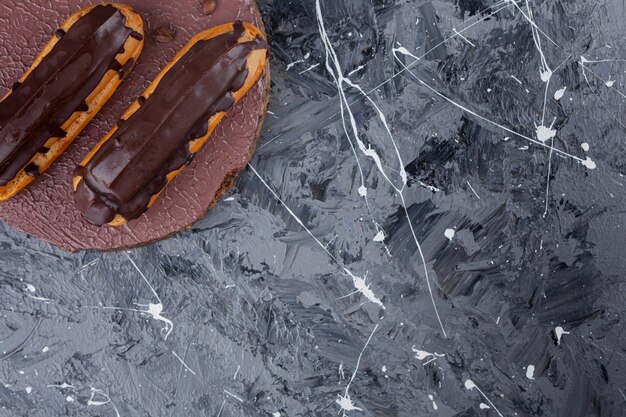 Köstliche Eclairs aus süßer Schokolade auf Holzstück.