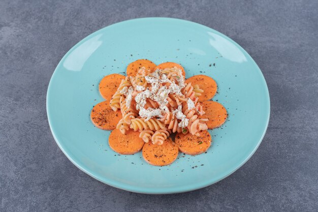 Köstliche Fusilli-Nudeln und Karotten auf blauem Teller.