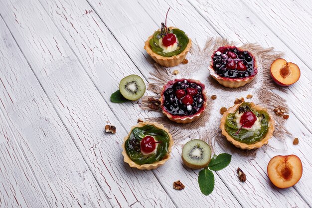 Köstliche gebackene Fruchtkörbe mit Beeren, exotischen Früchten, Grün und Nüssen