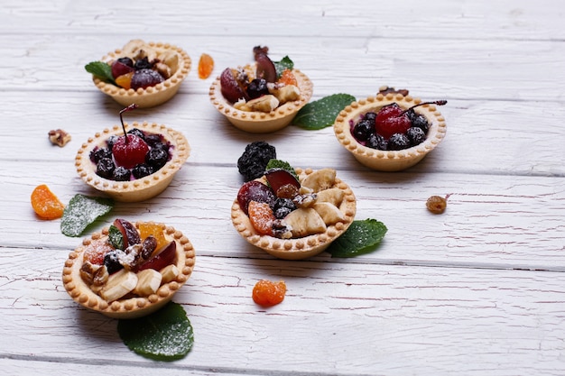 Köstliche gebackene Fruchtkörbe mit Beeren, exotischen Früchten, Grün und Nüssen