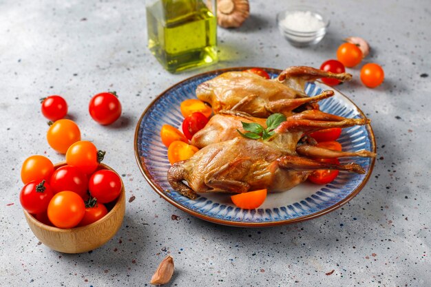 Köstliche gebratene Wachteln mit Kräutern und Kirschtomaten.