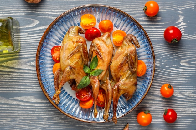 Köstliche gebratene Wachteln mit Kräutern und Kirschtomaten.