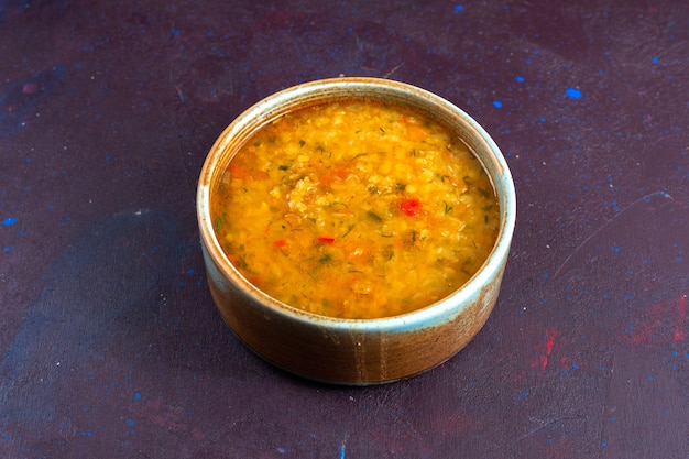 Köstliche Gemüsesuppe der halben Draufsicht innerhalb des runden Tellers auf dunklem Schreibtisch.