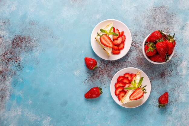Köstliche hausgemachte Erdbeerkuchenscheiben mit Sahne und frischen Erdbeeren, Draufsicht
