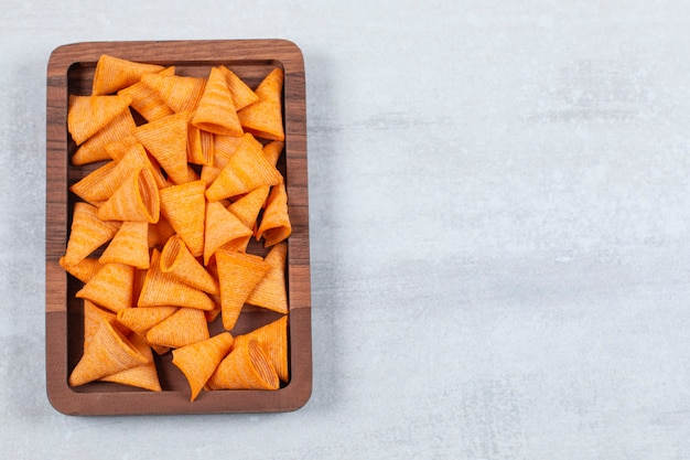 Köstliche knusprige Chips auf Holzplatte.