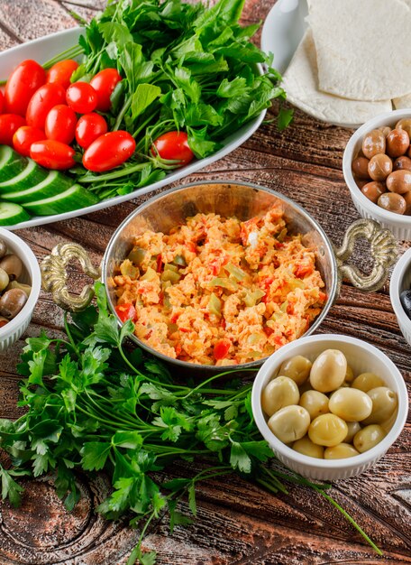 Köstliche Mahlzeit in einem Topf mit Salat, Essiggurken in Schalen hoher Winkelansicht auf einer vertikalen Holzoberfläche