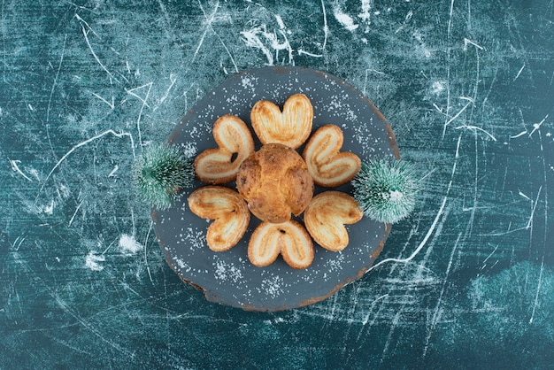 Köstliche Muffins und Kekse auf einem dunklen Holzbrett. Foto in hoher Qualität