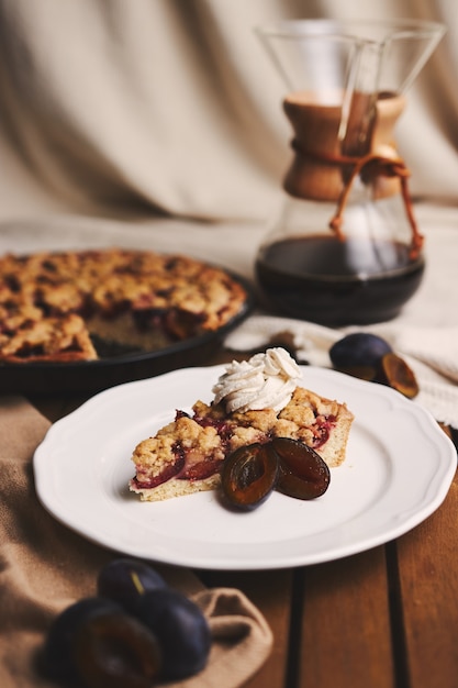 Köstliche Pflaumenpastete mit Chemex-Kaffee und Zutaten mit Stoff auf einem Holztisch mit Stoff