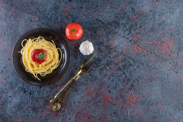 Köstliche Spaghetti mit Tomatensauce auf schwarzem Teller mit Besteck.