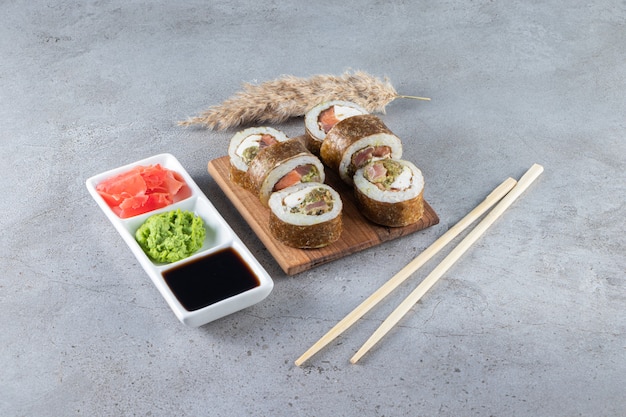 Köstliche Sushi-Rollen mit Thunfisch und eingelegtem Ingwer auf Steinhintergrund.