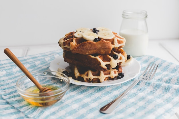 Köstliche Waffeln in der Nähe von Honig und Milchprodukten