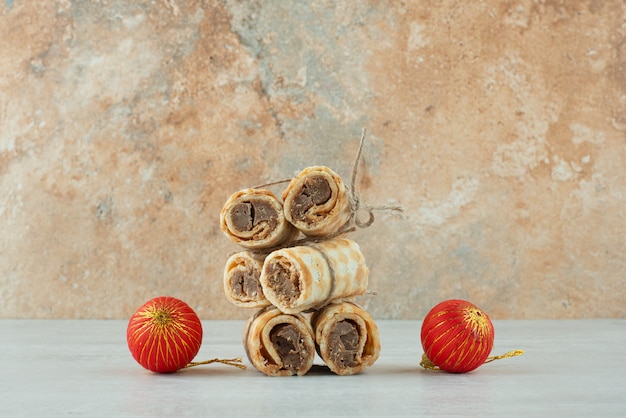 Köstliche Waffeln mit zwei roten Weihnachtskugeln auf Marmorhintergrund. Hochwertiges Foto