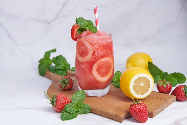 Köstlicher Erdbeer-Zitronen-Smoothie garniert mit frischer Erdbeere und Minze im Glas. Weicher Fokus. schöne Vorspeise rosa Erdbeere, Wohlbefinden und Gewichtsverlustkonzept.
