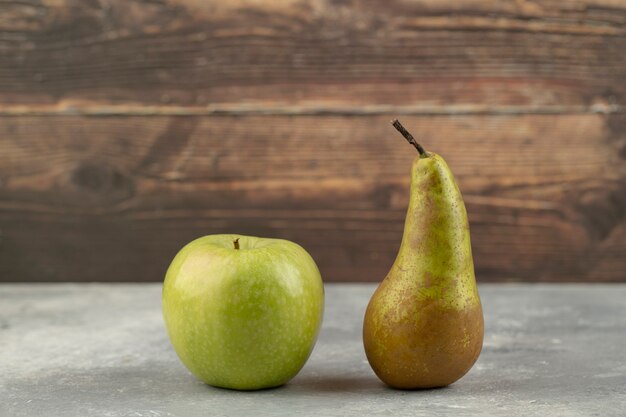 Köstlicher grüner Apfel und frische Birne auf Marmoroberfläche.