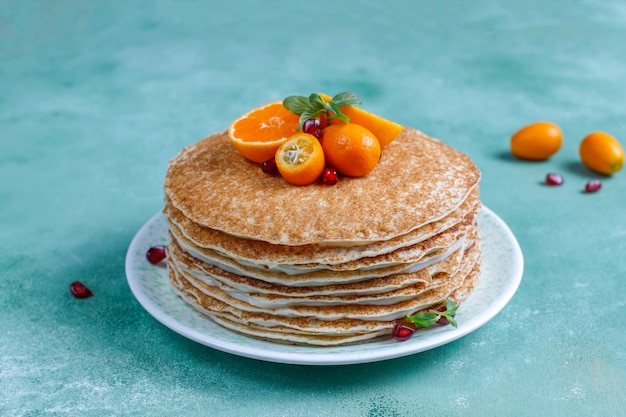 Köstlicher hausgemachter crpe-kuchen, dekoriert mit granatapfelkernen und mandarinen. Kostenlose Fotos