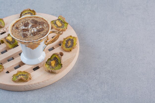 Kostenloses Foto köstlicher heißer kaffee in der weißen tasse mit getrockneter kiwi.