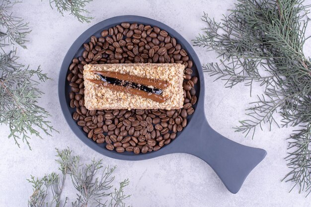 Köstlicher Kuchen auf dunklem Brett mit Kaffeebohnen. Foto in hoher Qualität