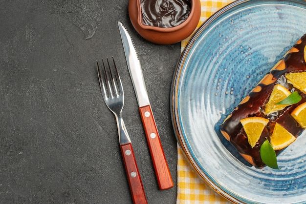 Köstlicher Kuchen, dekoriert mit Orange und Schokolade, serviert mit Gabel und Messer