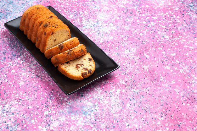 Köstlicher Kuchen der halben Draufsicht süß und lecker geschnitten auf rosa Schreibtisch.