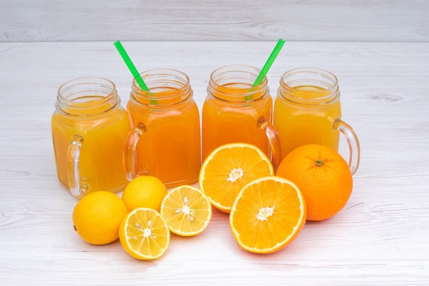 Köstlicher Orangen- und Zitronensaft auf weißem Holztisch