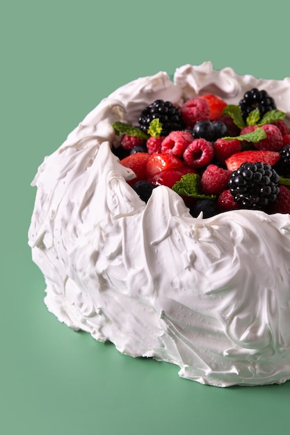 Köstlicher Pavlova-Kuchen mit Baiser und frischen Beeren auf grünem Hintergrund