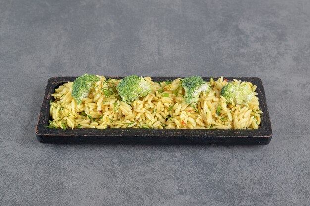 Köstlicher Reis mit Brokkoli auf schwarzem Teller. Foto in hoher Qualität