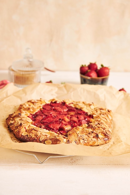 Köstlicher Rhabarber-Erdbeer-Gallat-Kuchen mit Zutaten auf einem weißen Tisch